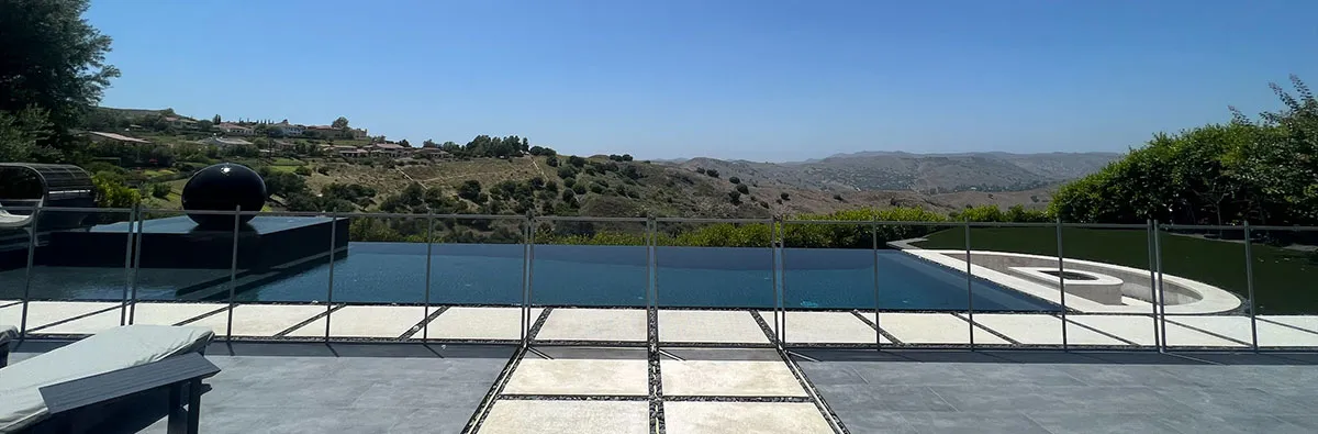 Glass balustrade along an infinity pool overlooking hills